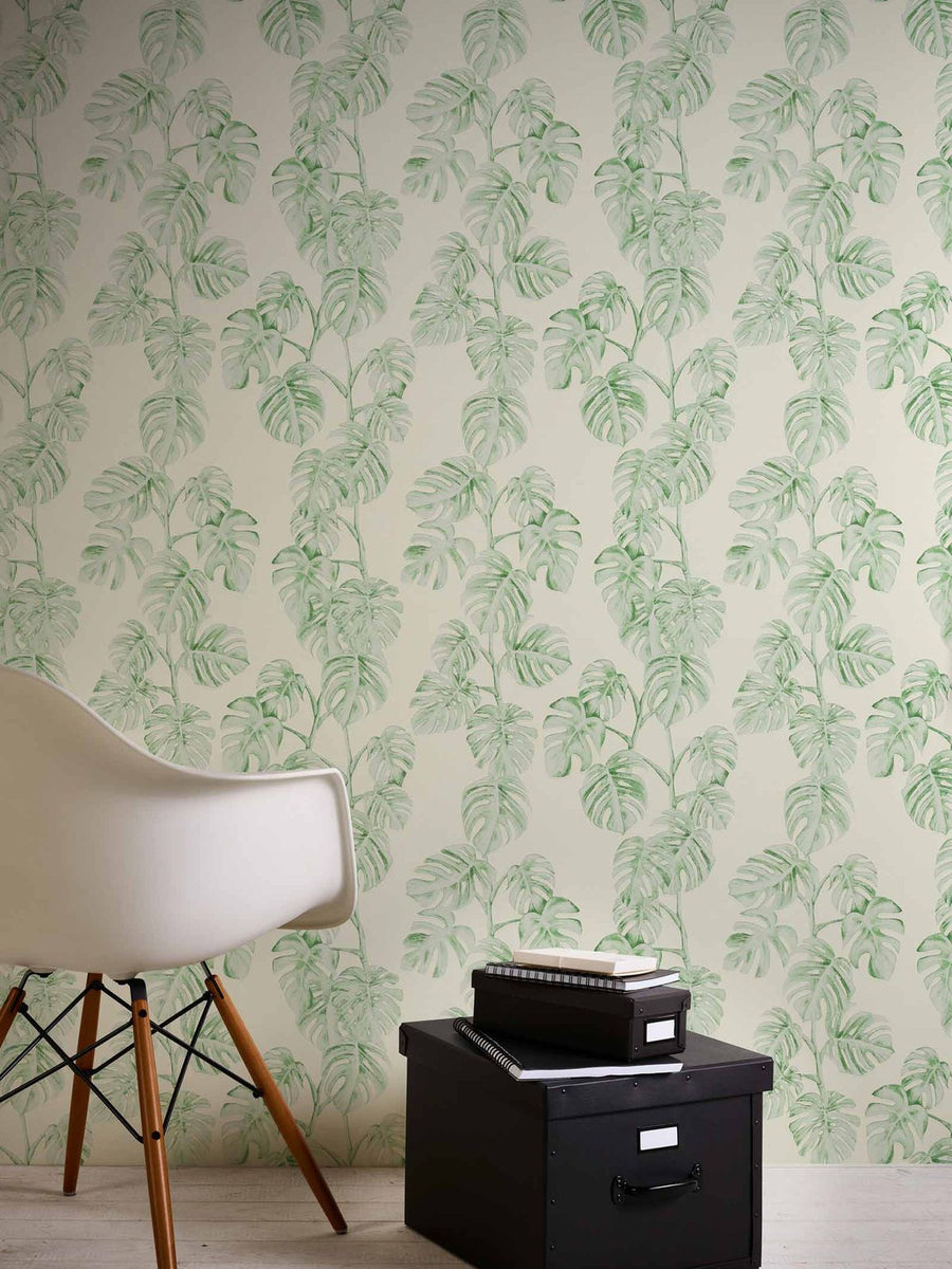 Room interior with green leafy wallpaper, black cabinet, and white chair.