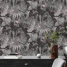 Wallpaper with dark floral pattern on a wall, desk, and chair in the foreground.